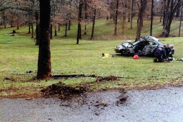 A crashed car on grass with trees in the background