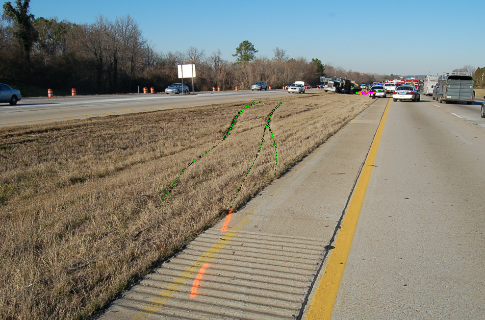 A grass median strip with tire tracks through the grass